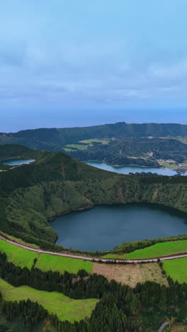 coming closer to a lake in the sleeping volcano crater. highway passes along the top edge of the mount. vertical video.