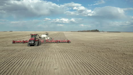 seeding machinery on the broad farm in saskatchewan, canada on a bright weather - fast drone shot