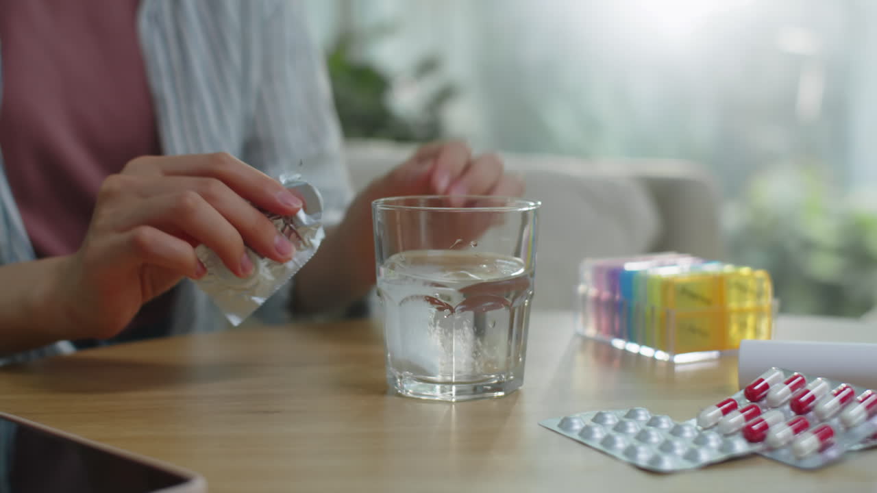 Woman Placing Effervescent Tablet in Glass with Water