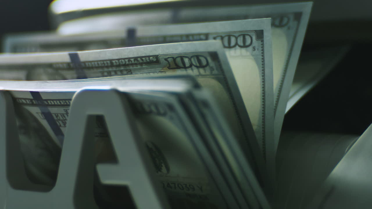 billetes de cien dólares saliendo de un dispensador de billetes