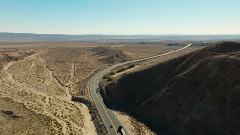 tráfico típico de la autopista 58 de california que serpentea a través de cañones de roca roja en el desierto de mojave - vista aérea