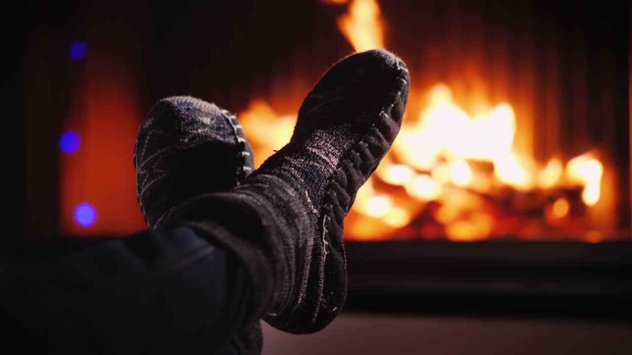 저녁에 불이 타오르는 벽난로 근처의 양말 신은 다리