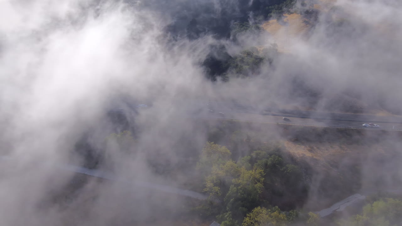niebla baja atrapada en el aire helado entre colinas en el sur de california cerca de san luis obispo - paso elevado aéreo
