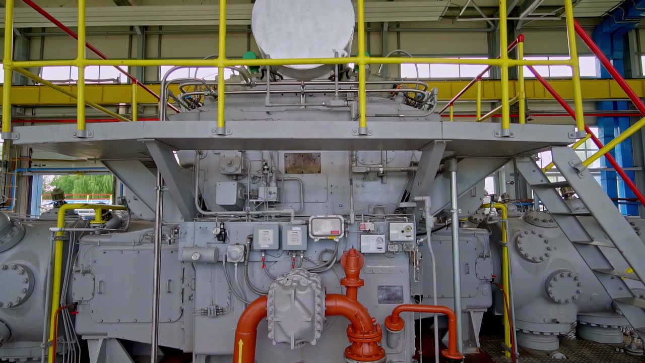Large gas compressor station with orange pipes operating in a modern industrial plant