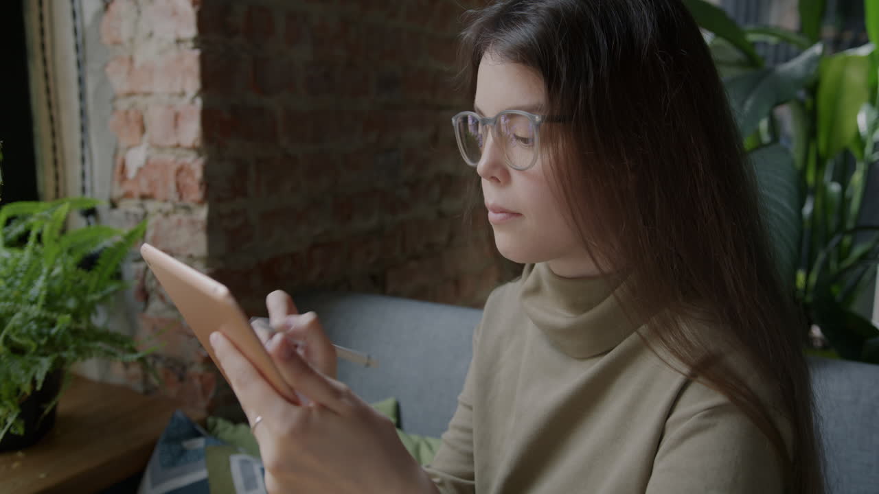 Young woman sketching on a digital tablet in a cafe