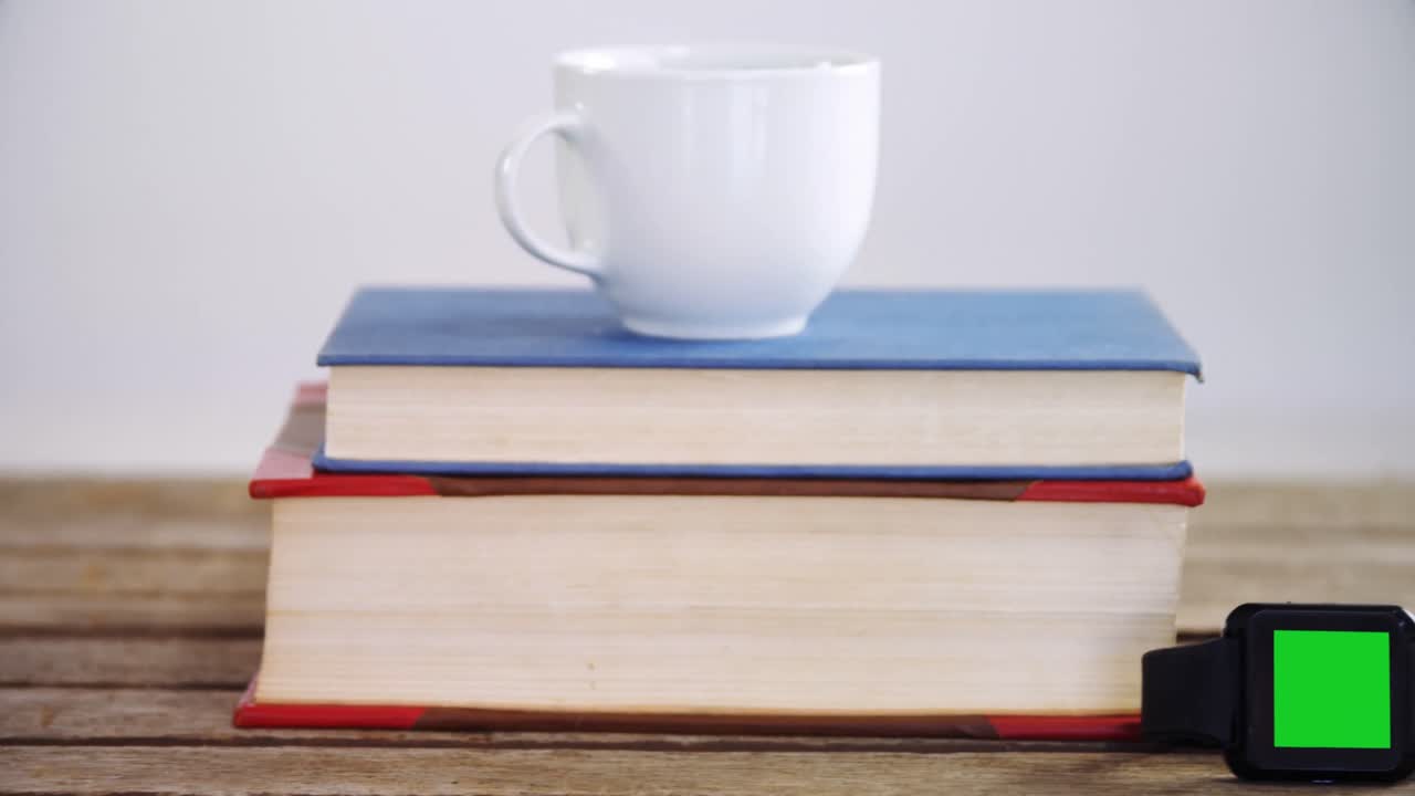 libros, taza de café, y reloj inteligente en una mesa de madera 4k