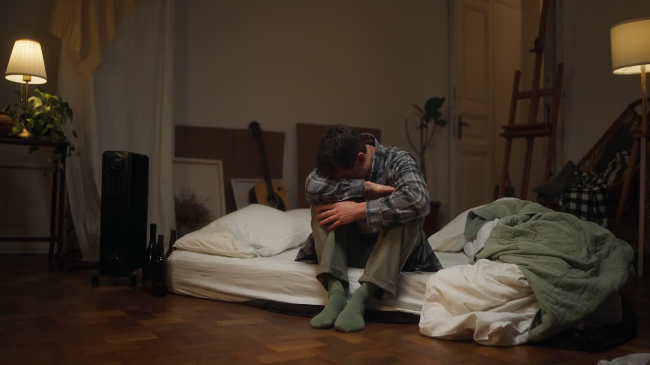Man sitting on a bed, looking sad