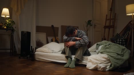 man sitting on a bed, looking sad