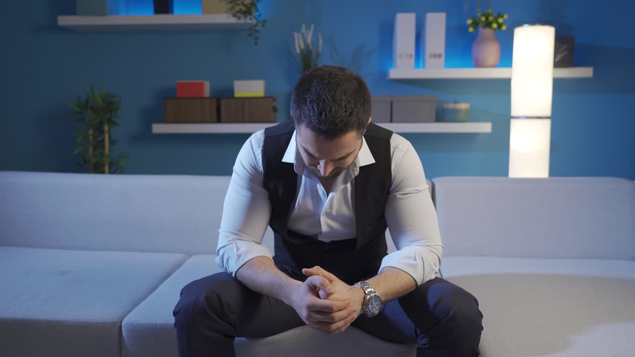 The man sitting in the living room late at night looks around with sadness and longing.