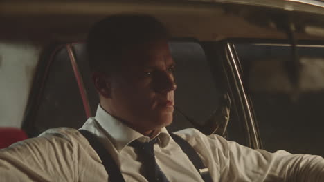 man driving a vintage car at night