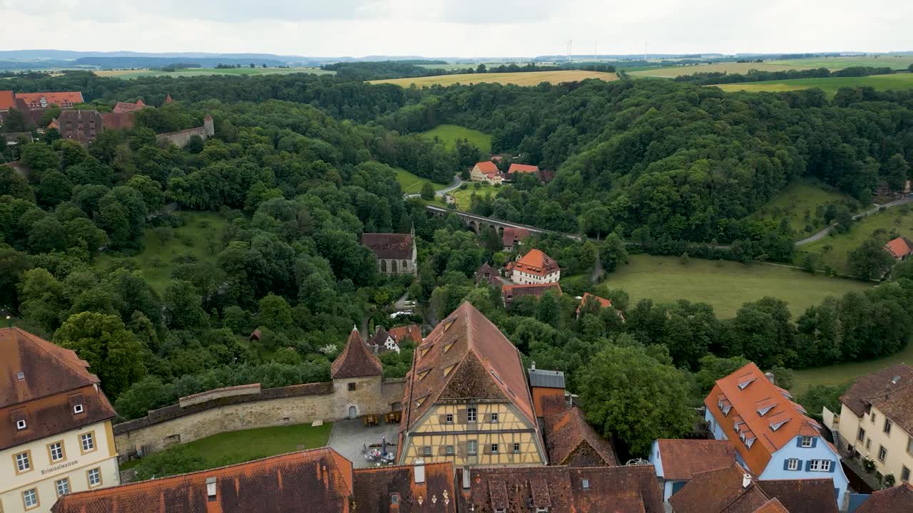 video aéreo de 4k de la antigua iglesia católica y el doble puente a lo largo del río tauber fuera de la ciudad amurallada de rothenburg, alemania