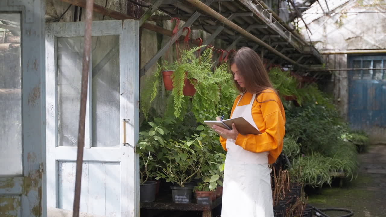 mujer jardinera comprobando las plantas en el invernadero