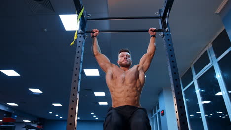 shirtless man pulling up on horizontal bar. crossfit athlete doing abs exercises on horizontal bar