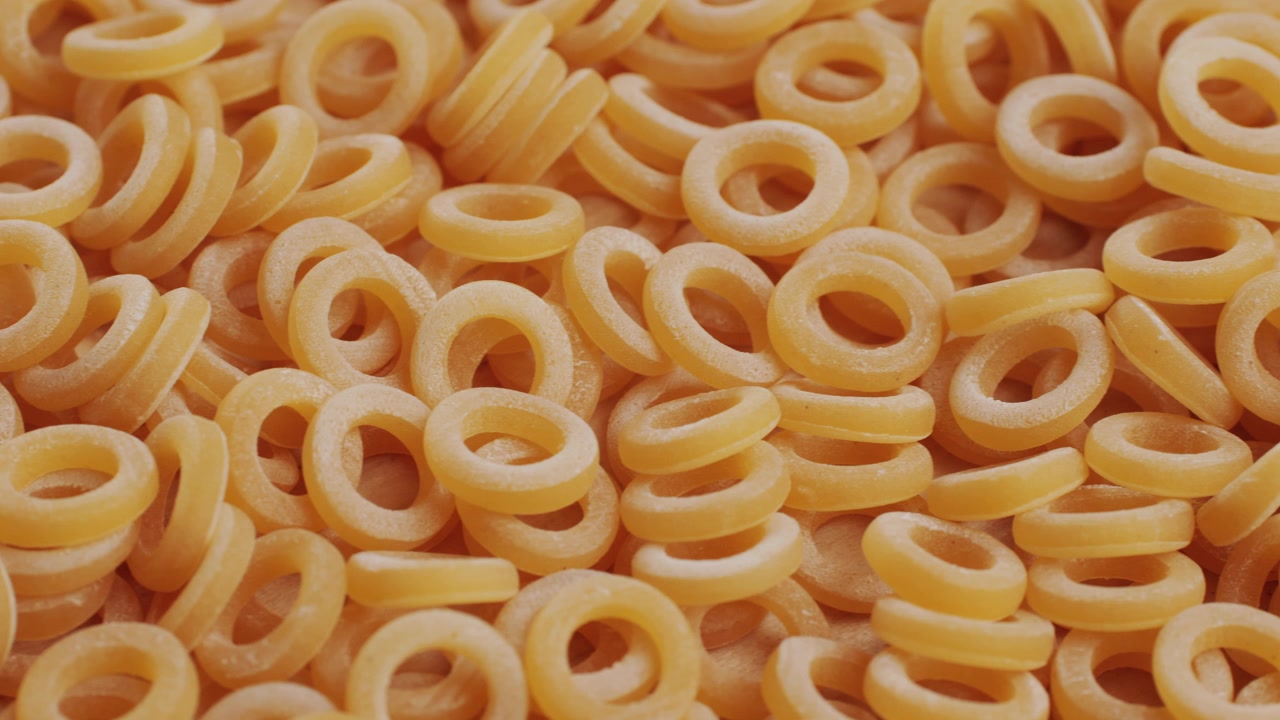 Pasta integrale biologica, maccheroni di semola di grano duro, penne rigate crude in una ciotola di legno. Filmato 4k di alta qualità