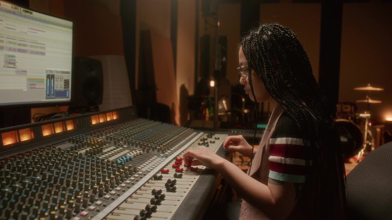 Asian Female Sound Engineer Operating Mixing Console in Recording Studio