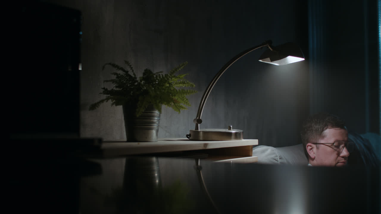 A sad man reads a book at night in his underwear