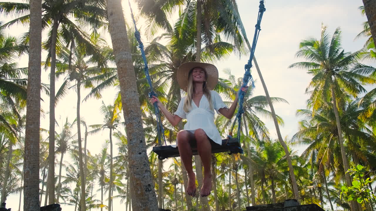 mujer balanceándose en un bosque tropical de palmeras