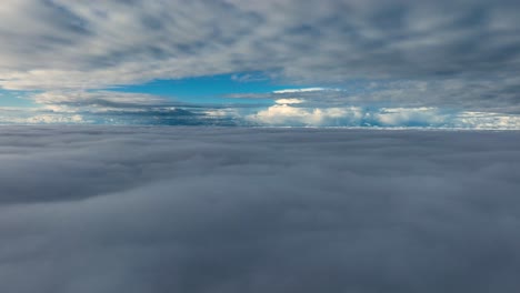 aerial view between cloud layers that looks almost like sailing over the ocean, with blue sky and white clouds in the distance