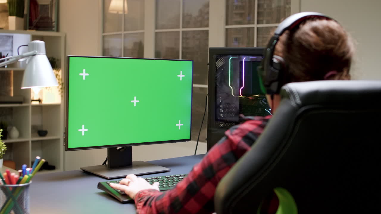 Gamer playing on a computer with a green screen