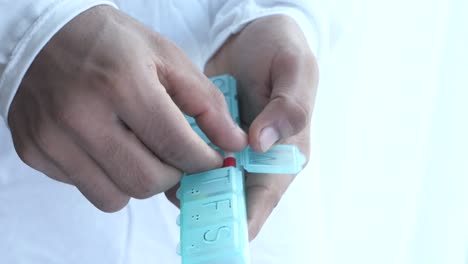 persona que toma medicamentos de un organizador de pastillas diarias