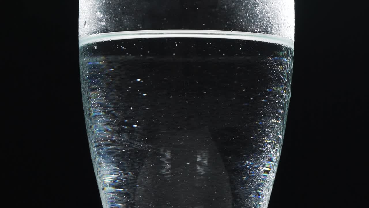 Glass of water rotating on black background