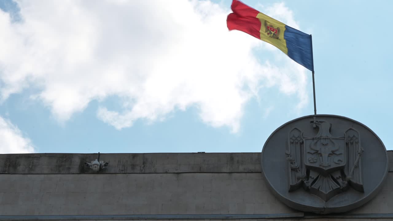 The flag of Moldova waving on top of a building with the sky on the background