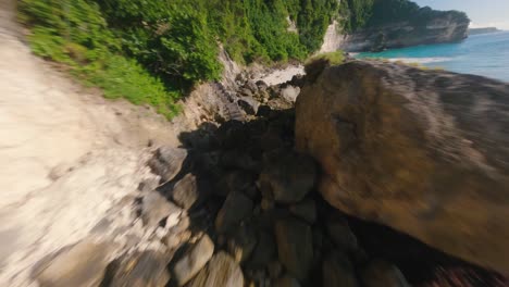 cámara lenta fpv disparó sobre las rocas y la playa de arena tropical en bali en un día soleado