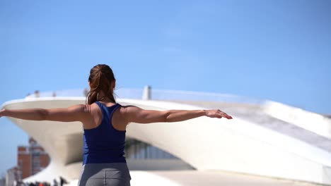 back view of young sportswoman stretching arms outdoor