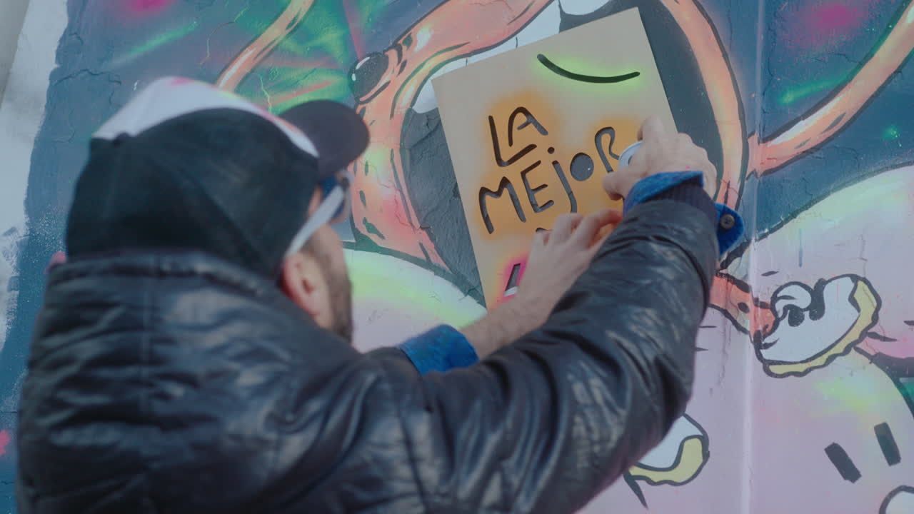 Graffiti Artist Using Stencil and Spray Paint while Drawing on the Wall