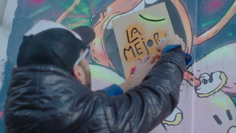 graffiti artist using stencil and spray paint while drawing on the wall