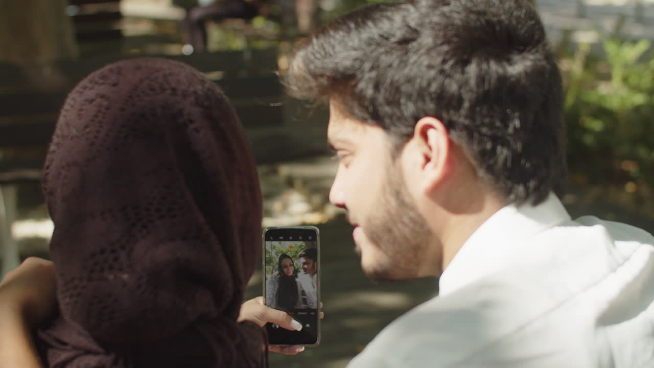 Close-up of young muslim couple doing selfie outside.