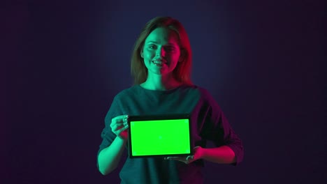 mujer sosteniendo una tableta con pantalla verde