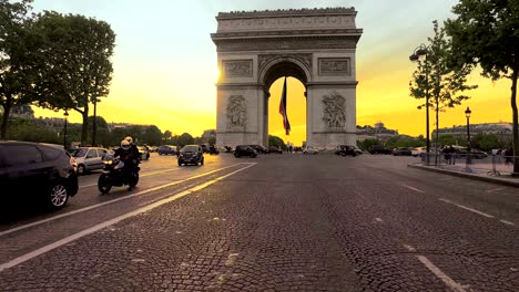 tourist pov on street crossing with view of beautiful sunset over arc de triomphe. paris, france