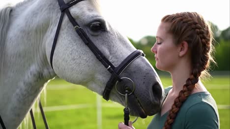 young woman with braided hair sharing a calm moment with her white horse.