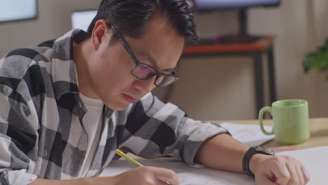 close up of asian male thinking about car concept then raising index finger while working on a car design sketch on table in the studio