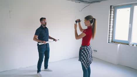 man jumps with level and pretty woman shooting in room