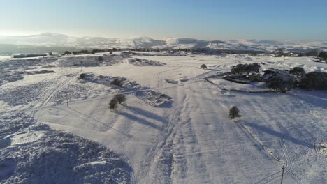 cubierto de nieve rural invierno campo pista huella sombras terreno vista aérea panorámica izquierda lentamente
