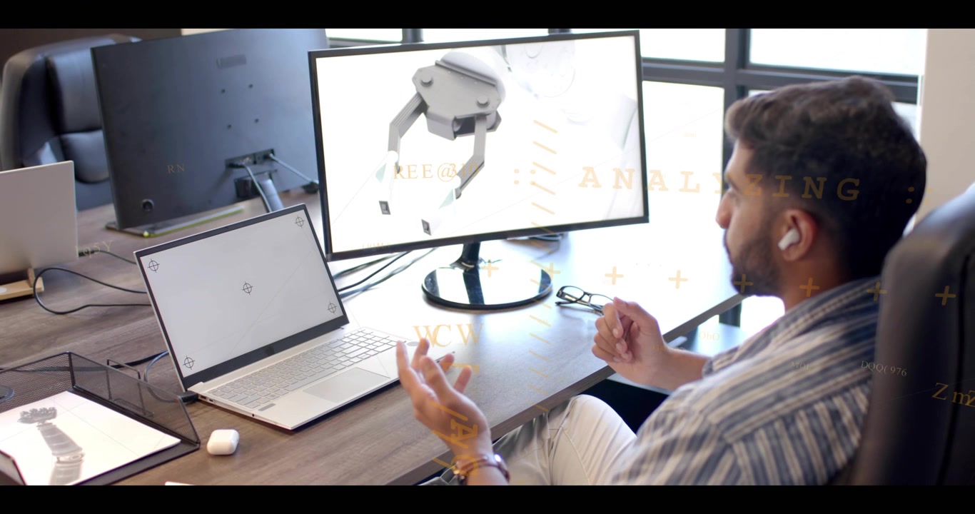 Engineer listening via earbud and gesturing with palms opening, reviewing robot gripper on monitor