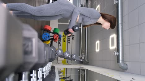 sporty woman lifting dumbbells in the gym near the mirror. beautiful body of a trained girl. sports, motivation
