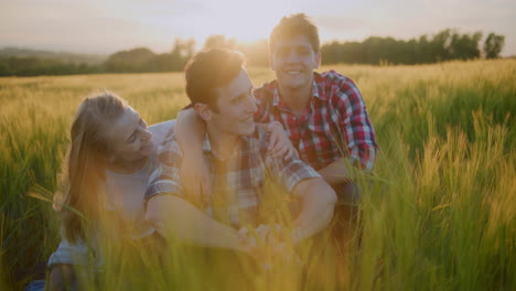 three friends enjoying in tall grass against sunset background