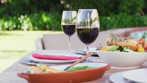 cerca de vasos de vino tinto y comida en la mesa en el jardín