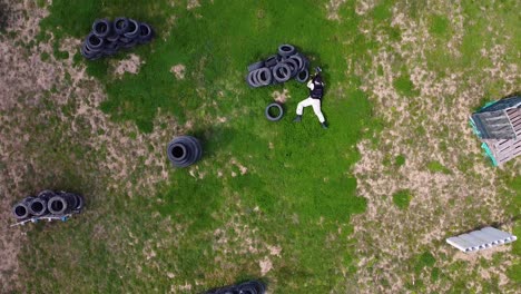 jugador de paintball haciendo un truco arrojándose a sí mismo en el campo mientras juega un tiro de avión no tripulado de juego de paintball