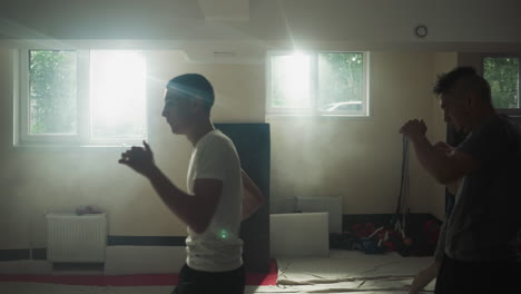 coach shows beginners correct hitting technique practicing boxing in basement. collective training session in sports club. direction from trainer to participants