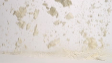 white flour falling onto white studio backdrop and splashing in slow motion 4k