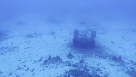 Cinematic wide dolly shot through a submarine porthole of a ship anchor on the ocean floor off the coast of the Big Island of Hawai&#039;i