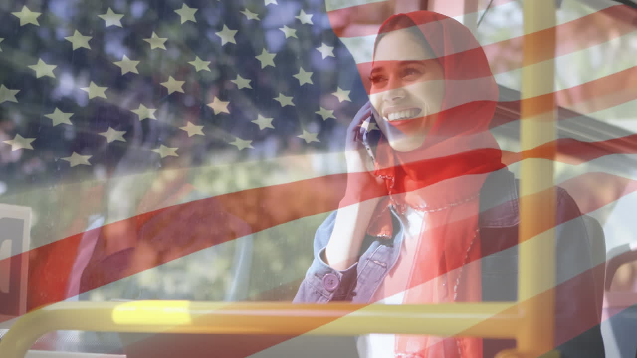 animación de la bandera estadounidense ondeando sobre una mujer biracial en hijab usando un teléfono inteligente