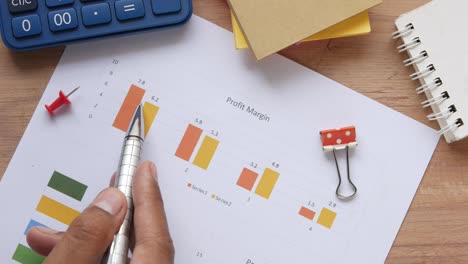 man hand with pen analyzing bar chart on paper