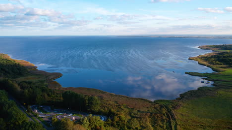 Aerial-view-overlooking-blue-Baltic-sea-surrounding-green-forest-island-landscape,-Poland