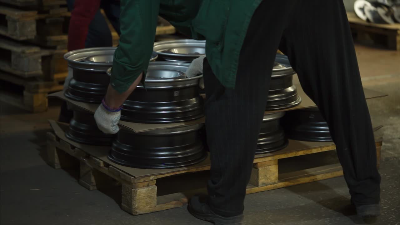 Worker Handling Car Wheels on Pallet in Warehouse