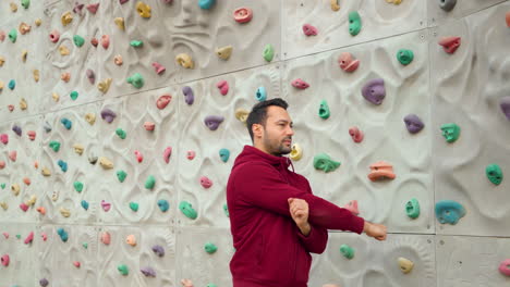 hombre escalador estiramiento calentamiento de las manos antes de la pared ejercicio de escalada en el campo deportivo al aire libre